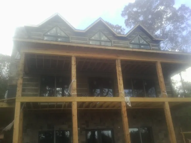 Dormers and porch framing on a large log home under construction — Roof Coating work by our crew in Wisdom