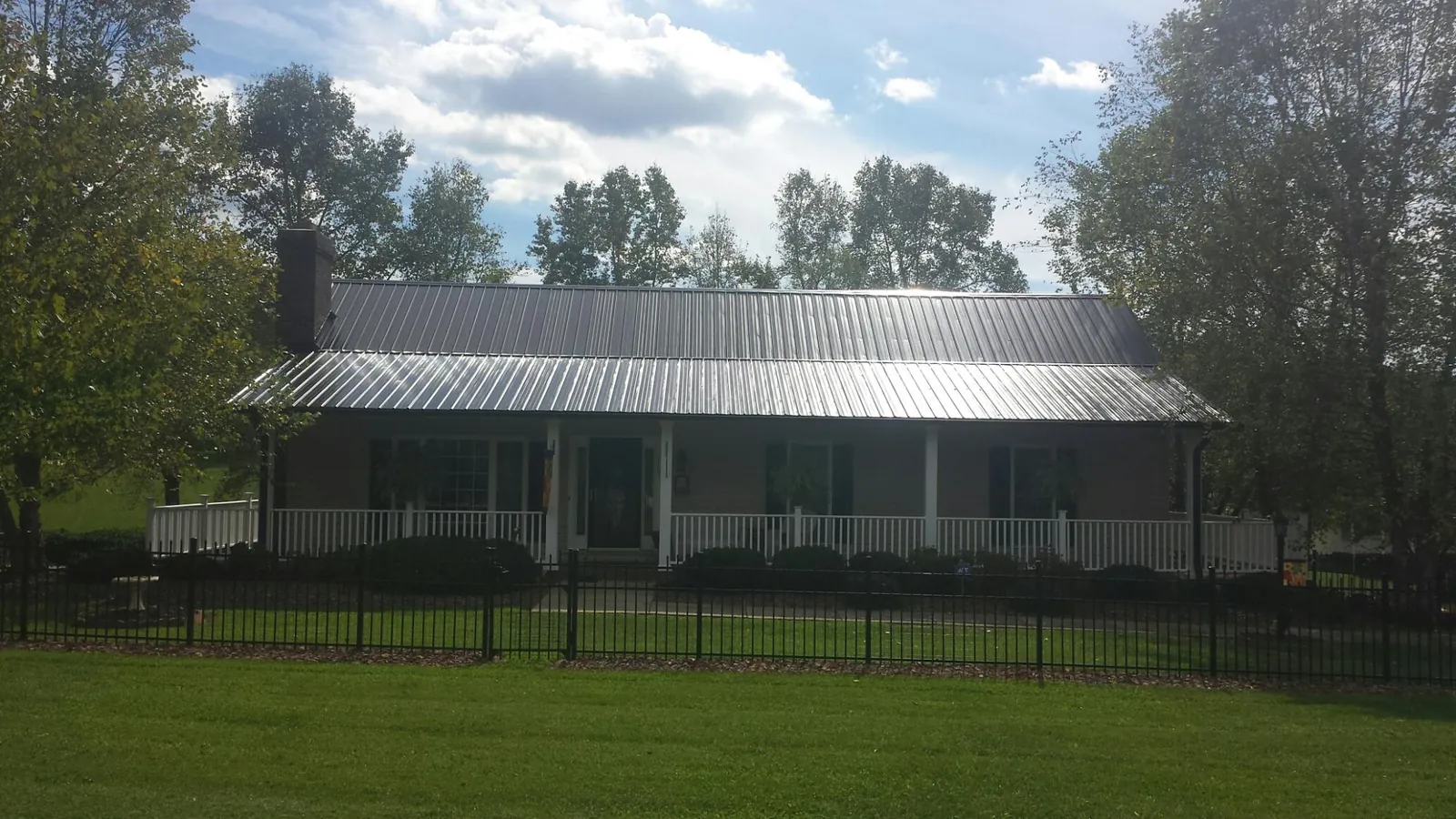 Gray metal roof on a brick ranch with a full width front porch — Gutter Guard Installation work by our crew in Wisdom